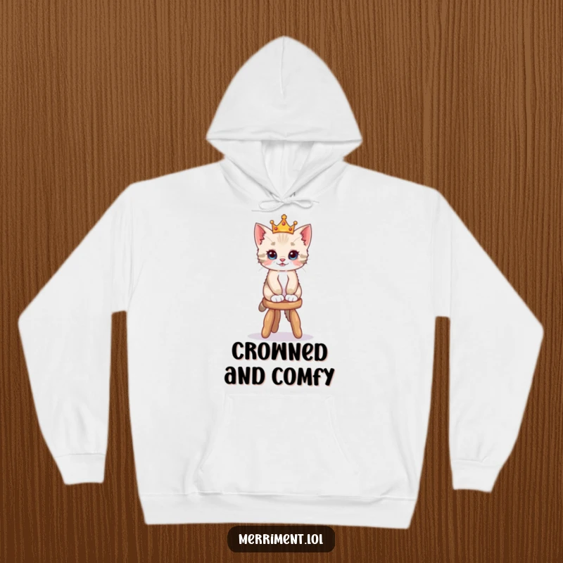 Funny hoodie design of a playful kitten in a tiny crown balancing on a wobbly stool, offering warmth and whimsical appeal.
